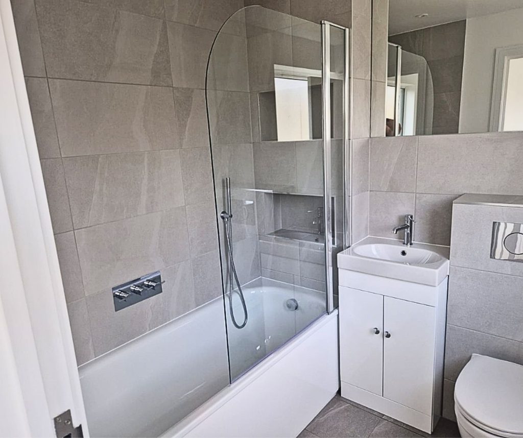Small bathroom with bath, overhead shower, glass screen and compact vanity unit
