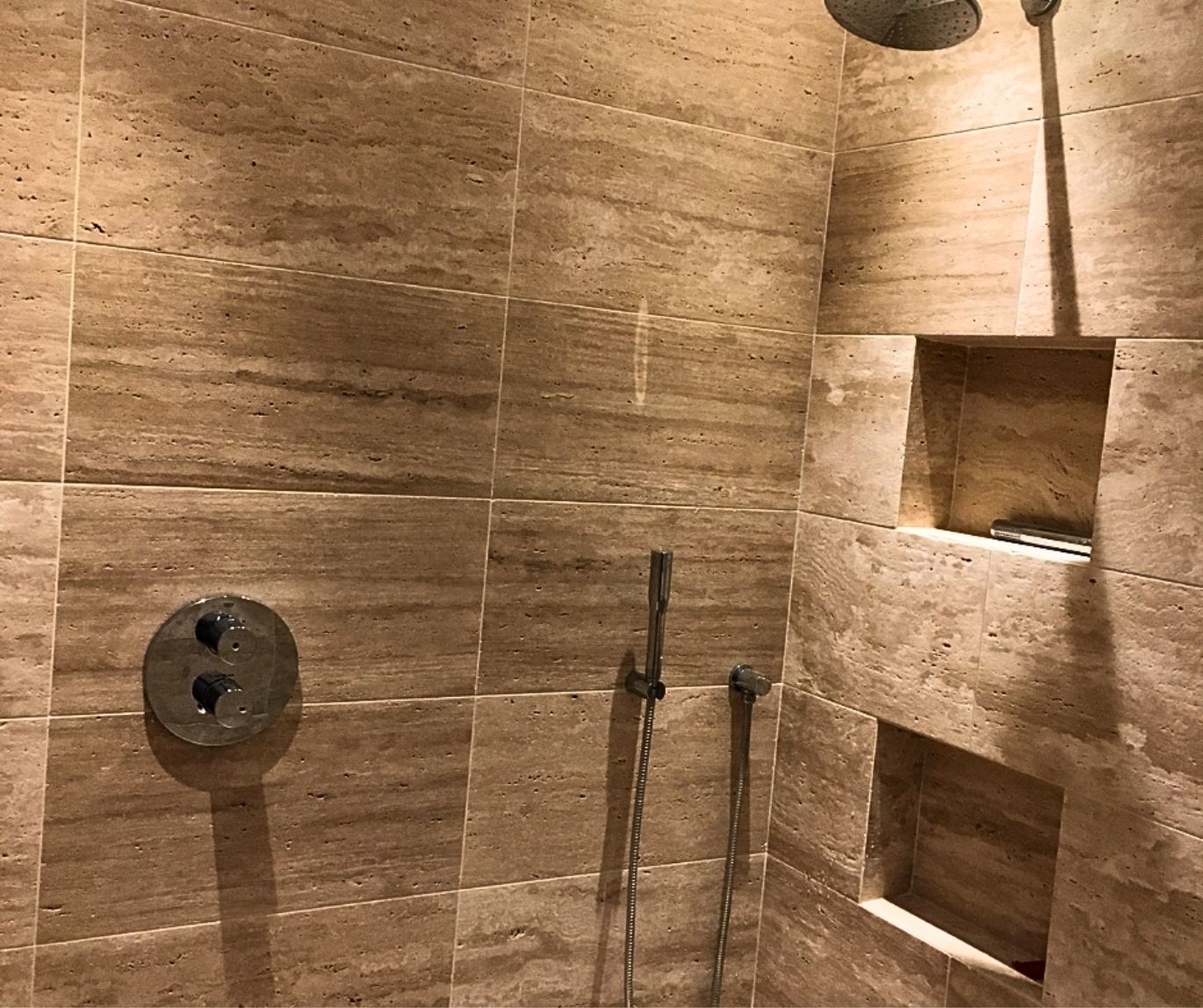 Walk-in shower finished with large-format stone-effect tiles and recessed storage niches