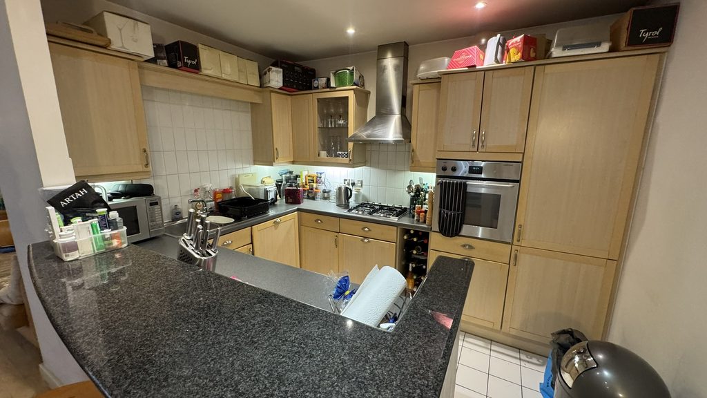 Kitchen before renovation with dated wooden units and dark worktops